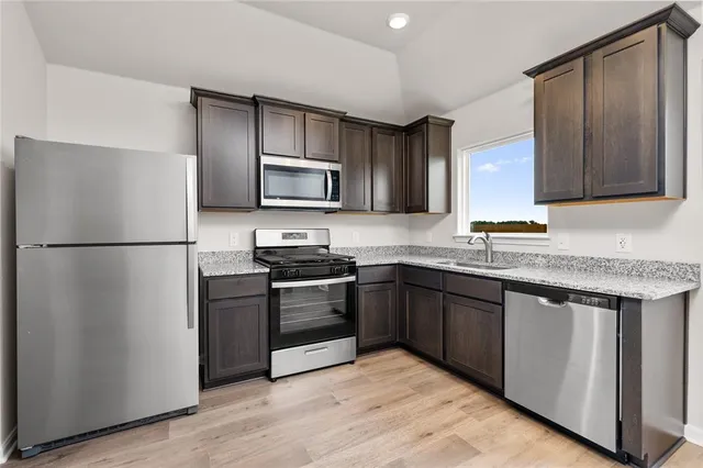 a kitchen with stainless steel appliances granite countertop a refrigerator stove a sink and a microwave