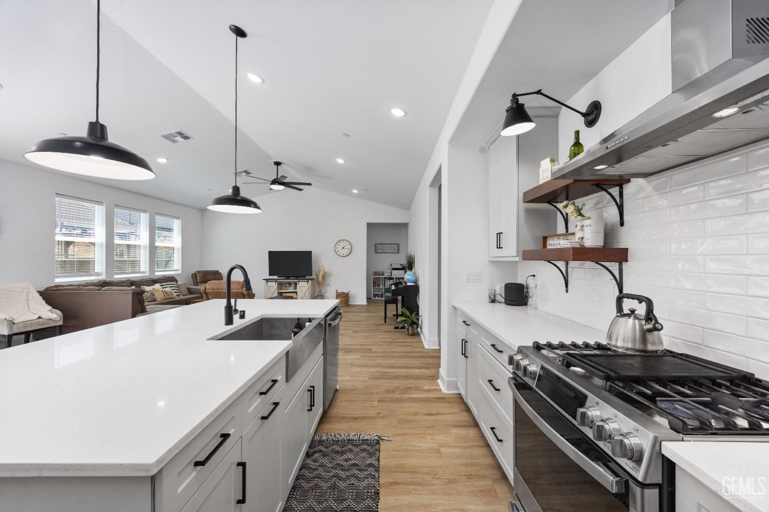 Undisclosed Address Tehachapi, CA 93561 - Photo 23 of 49 a large kitchen with stainless steel appliances a stove a sink dishwasher and a dining table with white cabinets