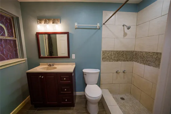 a bathroom with a granite countertop toilet sink and mirror