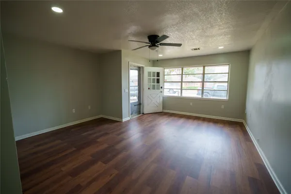 an empty room with wooden floor and windows