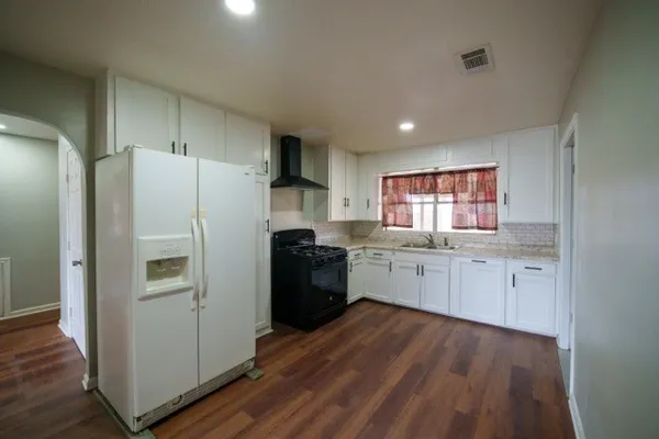 a kitchen with granite countertop a refrigerator stove top oven and sink