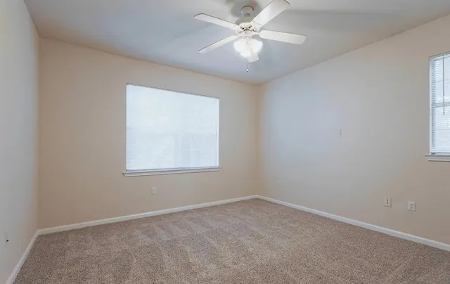 an empty room with a window and a fan