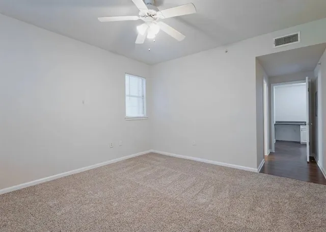 an empty room with a chandelier fan and windows