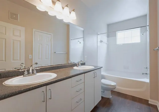 a bathroom with a granite countertop sink a toilet and bathtub