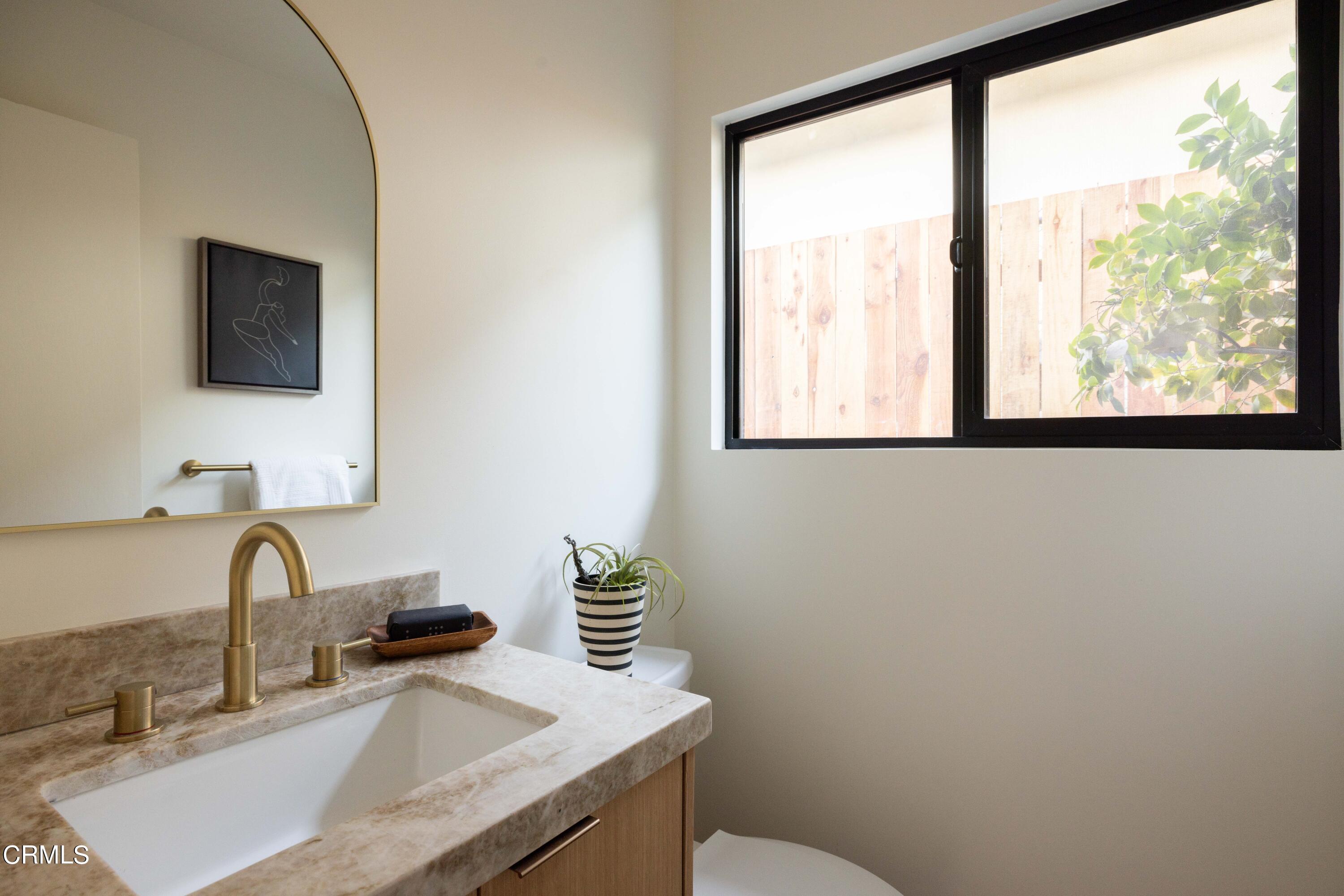 1054 Rutland Avenue Los Angeles, CA 90042 - Photo 22 of 27 a bathroom with a granite countertop sink a mirror and a window