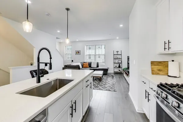 a kitchen with stainless steel appliances granite countertop a sink a stove and a wooden floors
