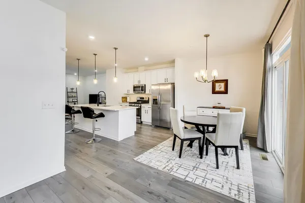 a kitchen with stainless steel appliances kitchen island granite countertop a table chairs sink and cabinets