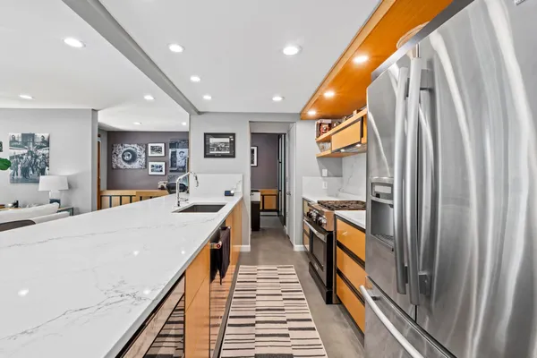 a kitchen with stainless steel appliances granite countertop sink a refrigerator and chairs