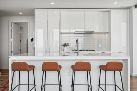 a kitchen with stainless steel appliances a stove a chair and white cabinets