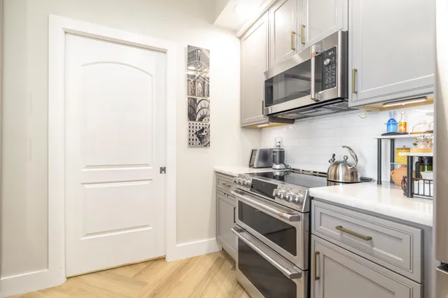 a kitchen with stainless steel appliances granite countertop white cabinets and a stove top oven