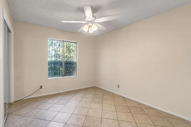 an empty room with windows and chandelier fan