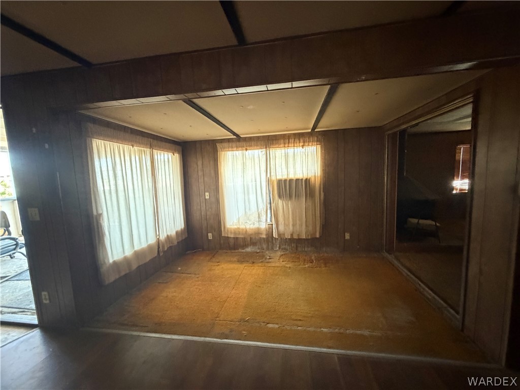 1666 Talc Road Bullhead City, AZ 86442 - Photo 12 of 61 Room featuring full-height wood-finish paneling, an exposed beam ceiling, and a large window with sheer curtains