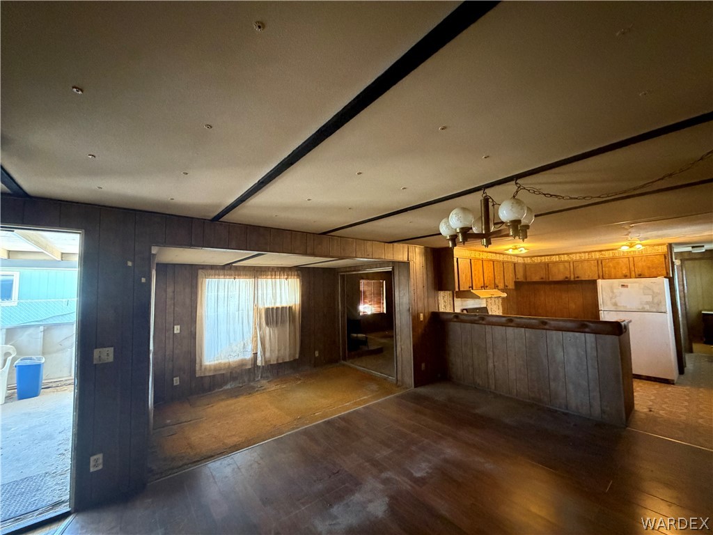 1666 Talc Road Bullhead City, AZ 86442 - Photo 15 of 61 Open-concept interior featuring wood-finish flooring, wood paneling, a built-in kitchen bar, upper cabinetry, and a globe chandelier