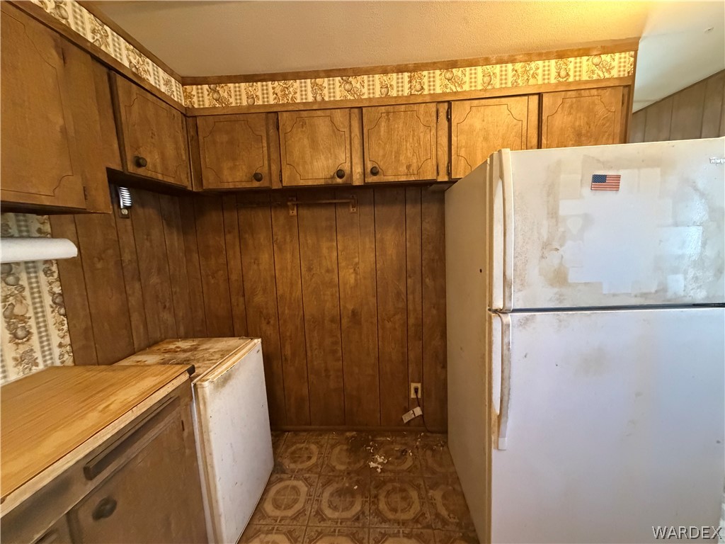 1666 Talc Road Bullhead City, AZ 86442 - Photo 20 of 61 Wood-paneled kitchen walls with patterned wallpaper trim, featuring upper wood cabinetry and patterned floor tiles