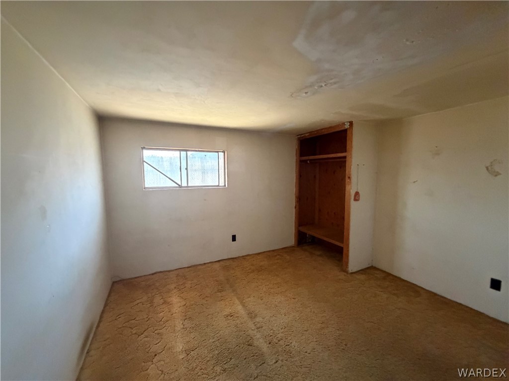1666 Talc Road Bullhead City, AZ 86442 - Photo 22 of 61 Room featuring a window, textured walls, and a built-in wood-finish closet with shelving and a hanging rod