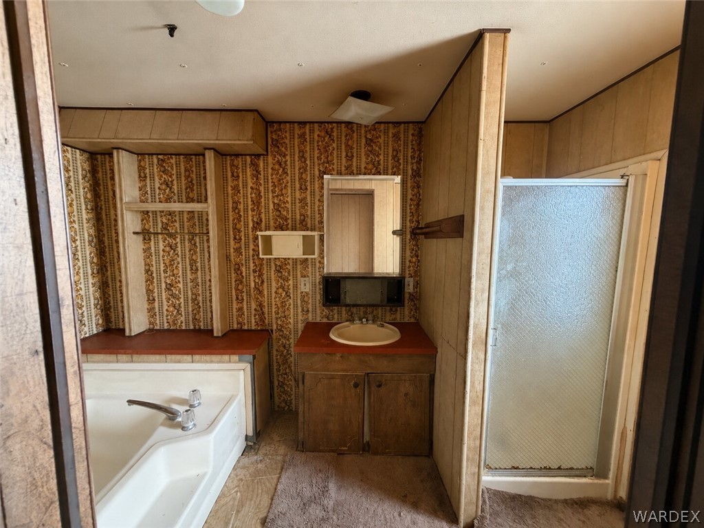 1666 Talc Road Bullhead City, AZ 86442 - Photo 26 of 61 Bathroom featuring a built-in tub, a separate shower stall, a vanity with a drop-in sink, and patterned wallpaper