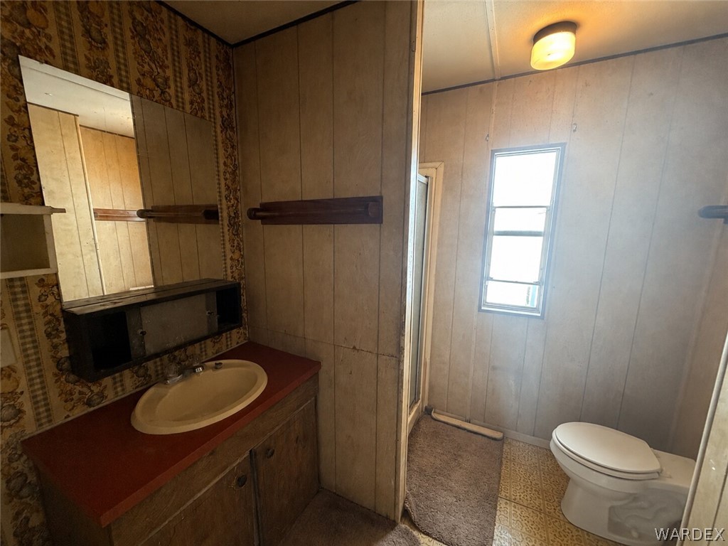 1666 Talc Road Bullhead City, AZ 86442 - Photo 28 of 61 Bathroom featuring a vanity with a red countertop and oval sink, a wall-mounted mirror, a toilet, a window, and overhead lighting