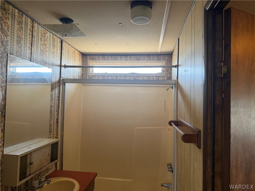 1666 Talc Road Bullhead City, AZ 86442 - Photo 32 of 61 Bathroom featuring a built-in shower stall, a vanity with a red countertop, and a wall-mounted mirror