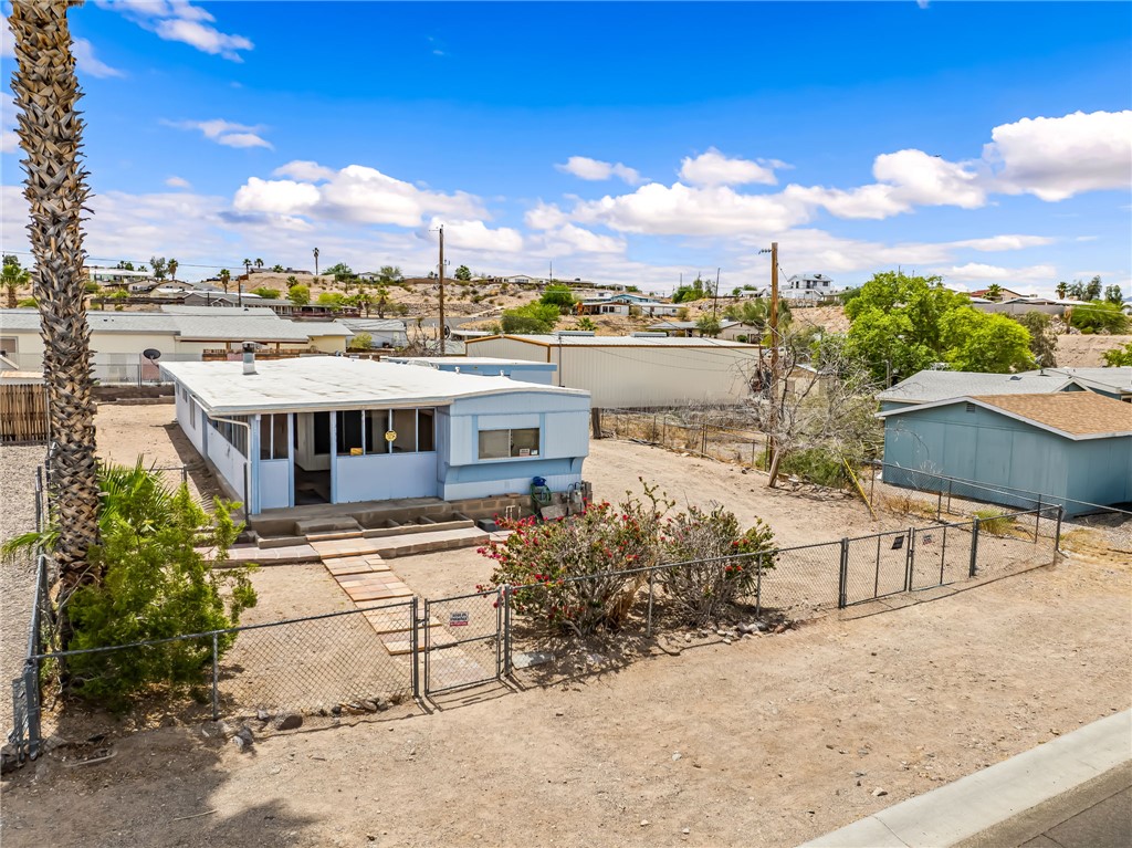 1666 Talc Road Bullhead City, AZ 86442 - Photo 55 of 61 Light blue exterior residence with a white roof, featuring a fenced front yard