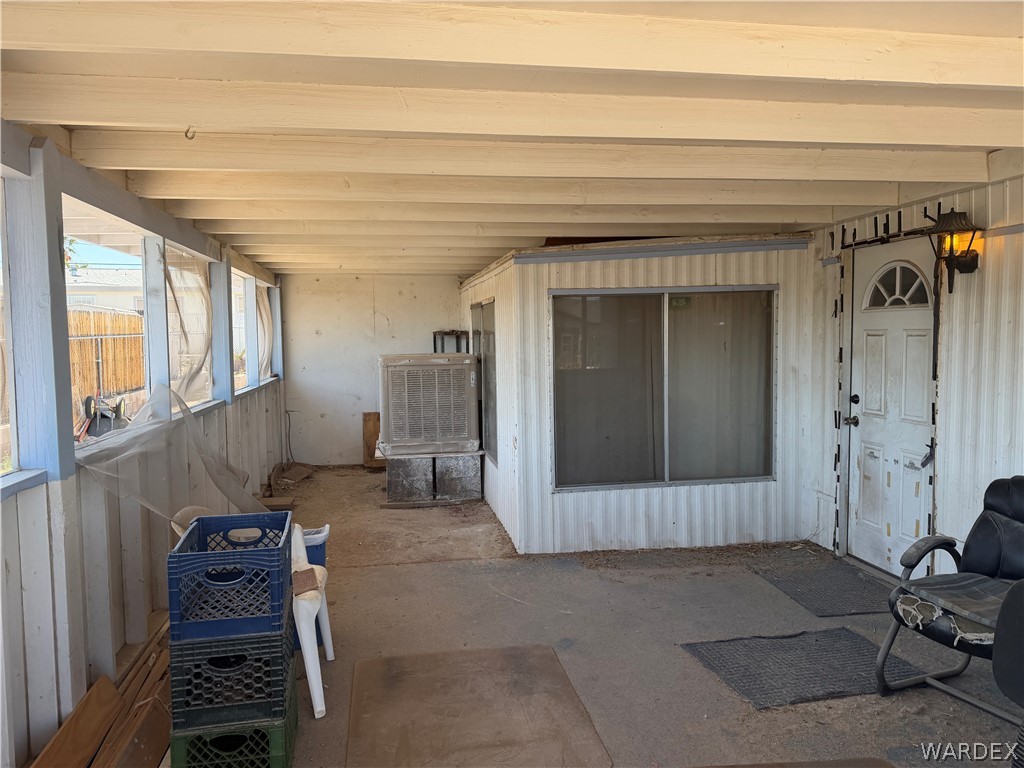 1666 Talc Road Bullhead City, AZ 86442 - Photo 8 of 61 Covered outdoor patio with a concrete slab, exposed ceiling beams, and a white exterior door with an arched transom