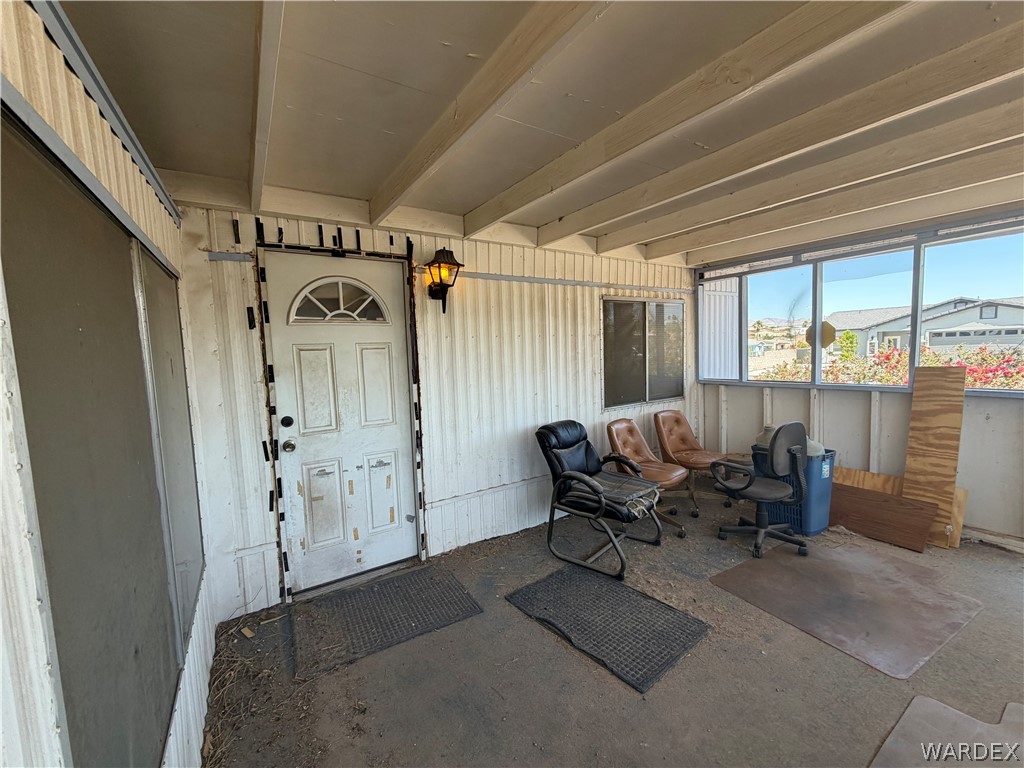 1666 Talc Road Bullhead City, AZ 86442 - Photo 9 of 61 Enclosed patio featuring a screened entry, exposed beam ceiling, exterior wall lantern, and a series of windows