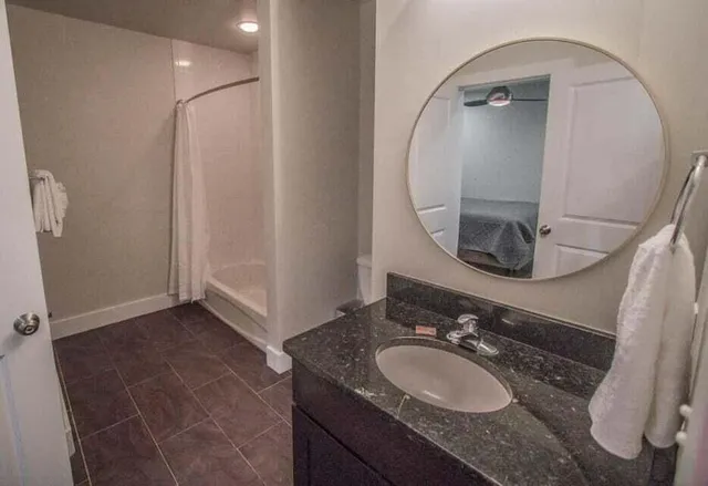 a bathroom with a granite countertop sink a mirror and a shower