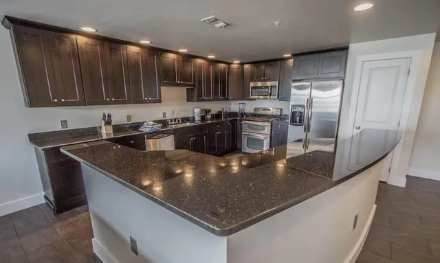 a kitchen with stainless steel appliances granite countertop a sink a stove and a refrigerator