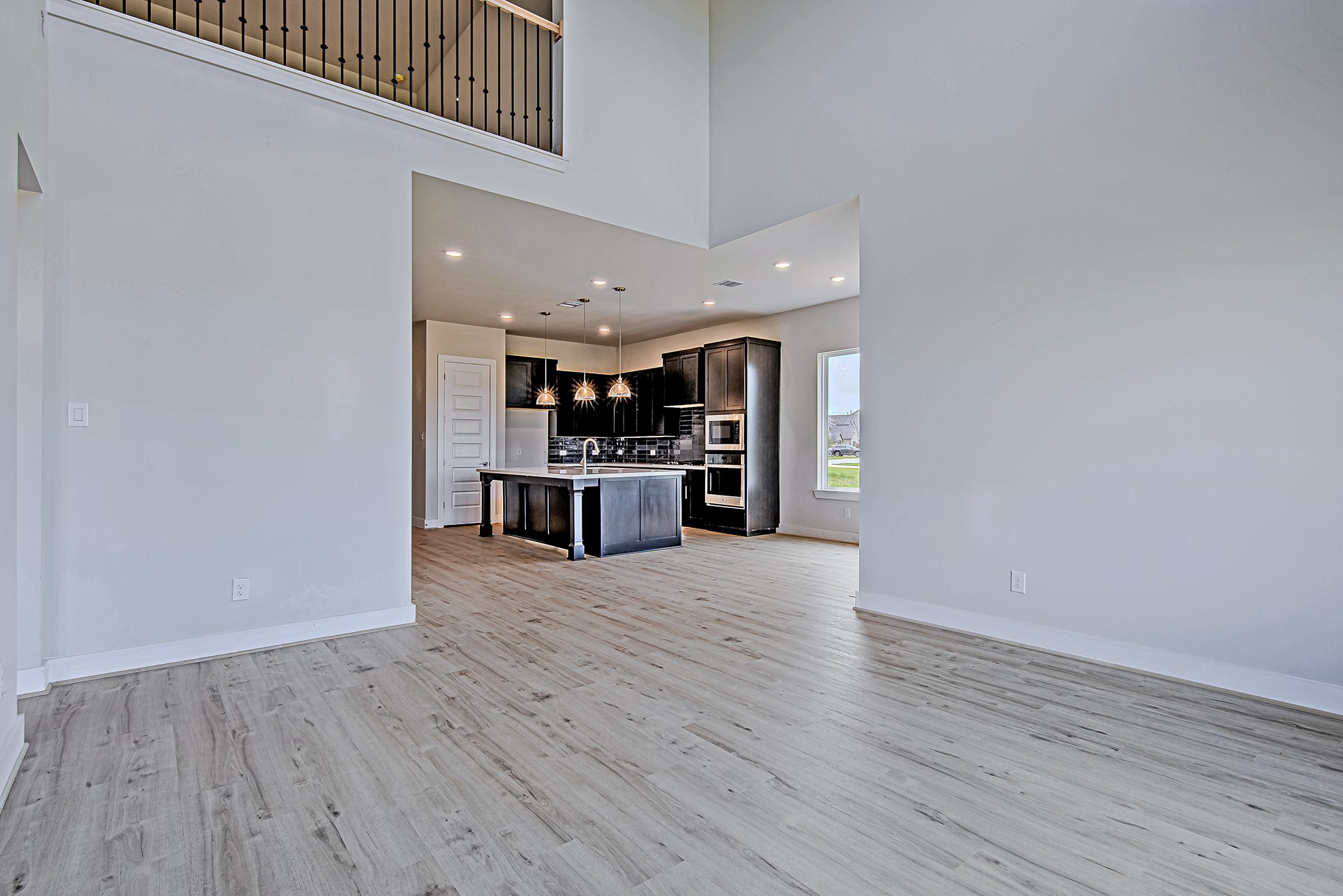 177 Peninsula Point Drive Montgomery, TX 77356 - Photo 12 of 40 Spacious living area seamlessly connects to the kitchen and dining spaces, accented by volume ceilings and a sleek iron railing on the second-floor landing.