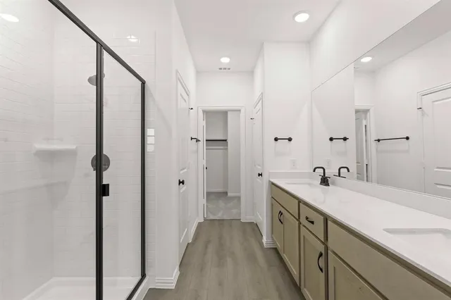 a spacious bathroom with a double vanity sink a mirror and a shower
