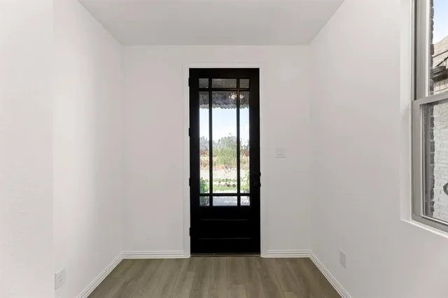 a view of an empty room with wooden floor and a window