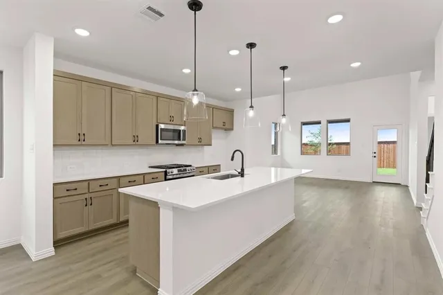a large kitchen with stainless steel appliances granite countertop a sink a stove and a wooden floors