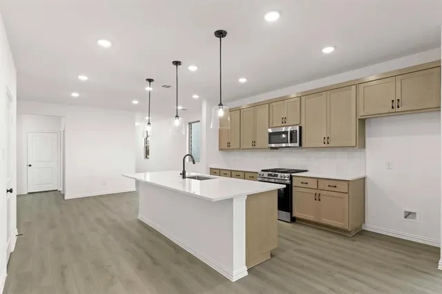 a large kitchen with stainless steel appliances granite countertop a sink a stove and a refrigerator