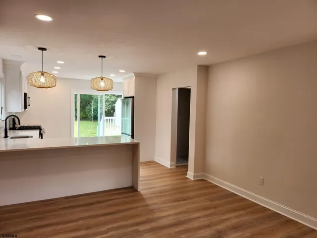 a view of an empty room with wooden floor fireplace and a window