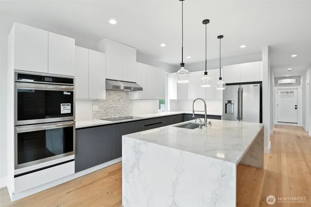 a kitchen with stainless steel appliances granite countertop a sink a stove and a wooden floor