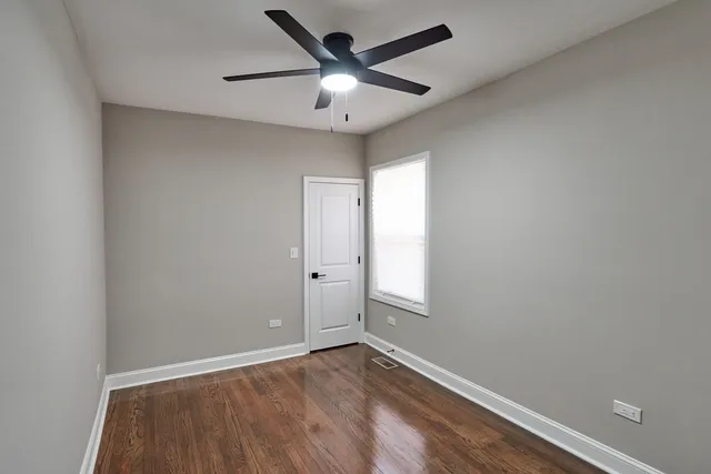 an empty room with window and ceiling fan