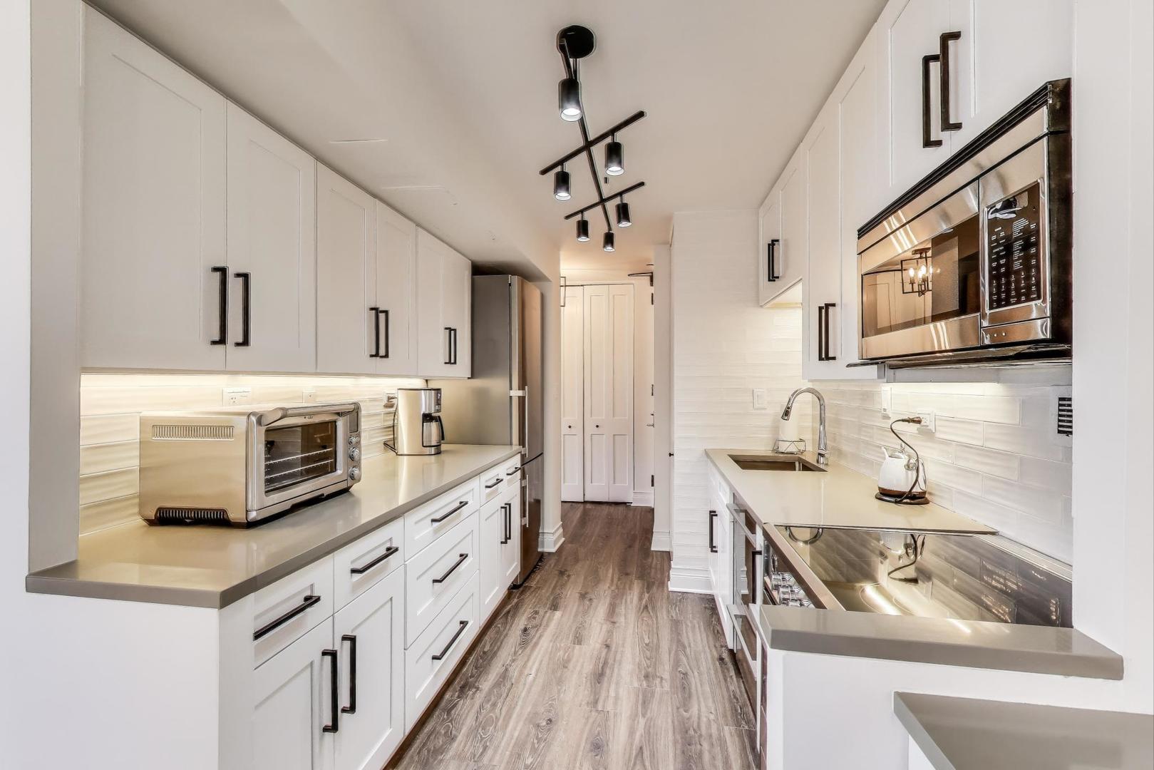1310 North Ritchie Court, Unit 9D Chicago, IL 60610 - Photo 9 of 27 a kitchen with stainless steel appliances a stove microwave and a white cabinets