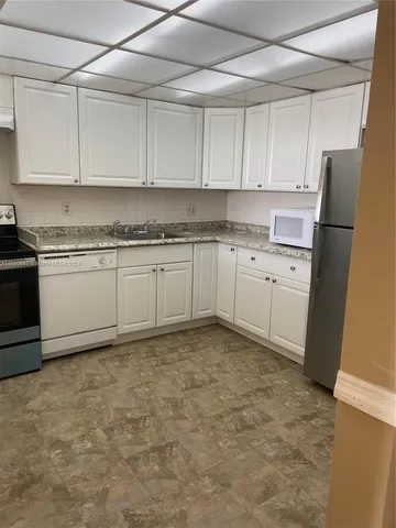a kitchen with granite countertop cabinets stainless steel appliances and a sink