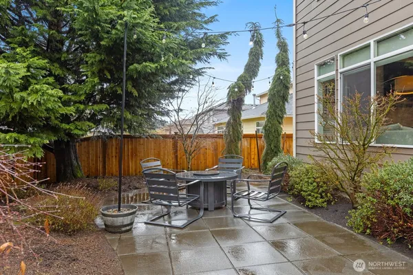 a view of a patio with table and chairs potted plants and a large tree