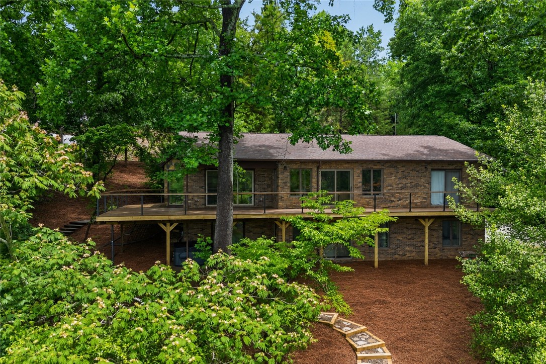 304 Lakeside Drive Seneca, SC 29672 - Photo 1 of 49 Perched among verdant trees, this brick dwelling features a spacious deck overlooking a natural landscape.
