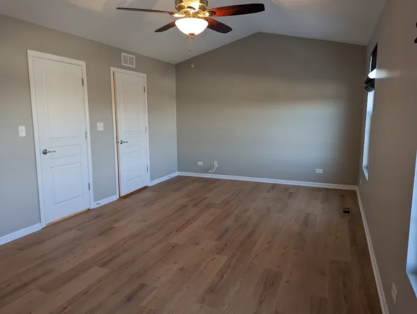 wooden floor in an empty room with a chandelier fan