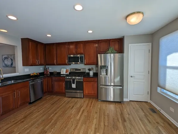a kitchen with granite countertop wooden floors stainless steel appliances and a window