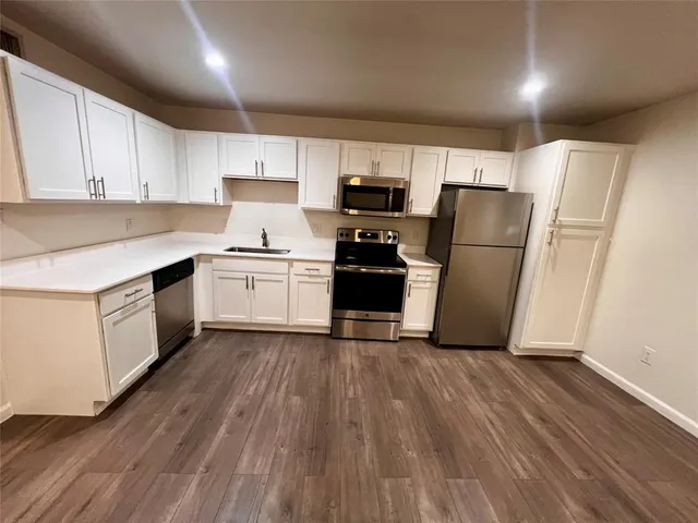 a kitchen with a refrigerator a sink and dishwasher with wooden floor