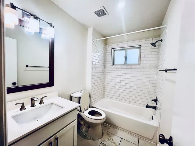 a bathroom with a bathtub shower sink vanity and toilet