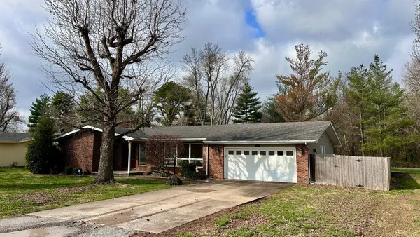 a front view of a house with a garden and trees