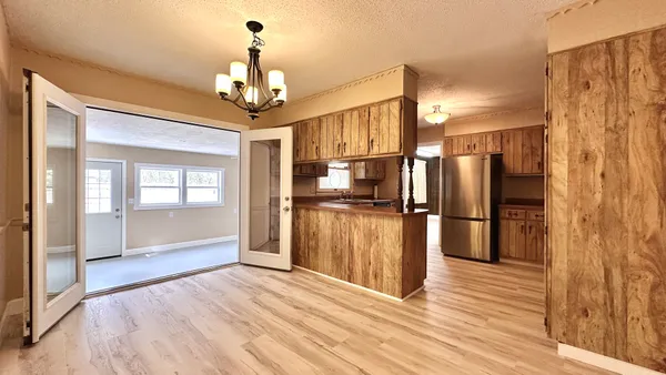 a view of a kitchen with refrigerator and wooden floor