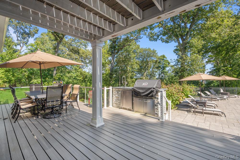5 Coon Hollow Road Lloyd Harbor, NY 11743 - Photo 38 of 43 a view of a patio with table and chairs under an umbrella with wooden floor