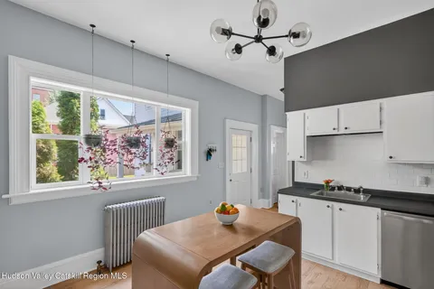 a kitchen with stainless steel appliances a stove a refrigerator and white cabinets with wooden floor