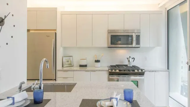 a kitchen with granite countertop a sink stove and microwave