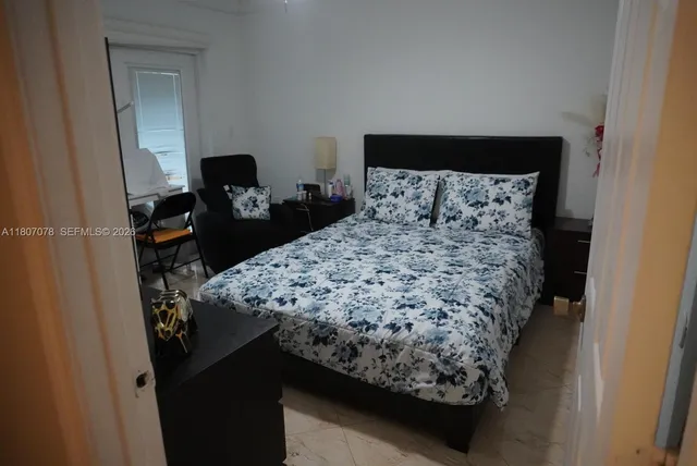 a bed sitting in a bedroom next to a window with tv on it