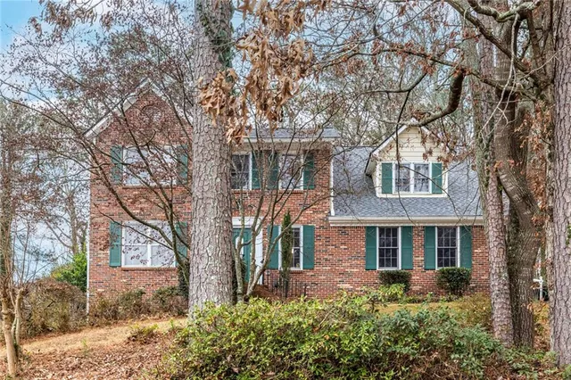 a front view of house with yard and trees around